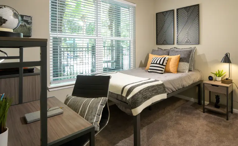 a furnished student apartment bedroom with a study desk