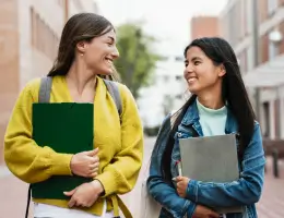 two women walking outside and holding notebooks