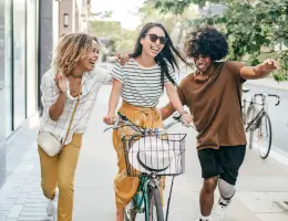 three women, one on a bicycle, laughing outside